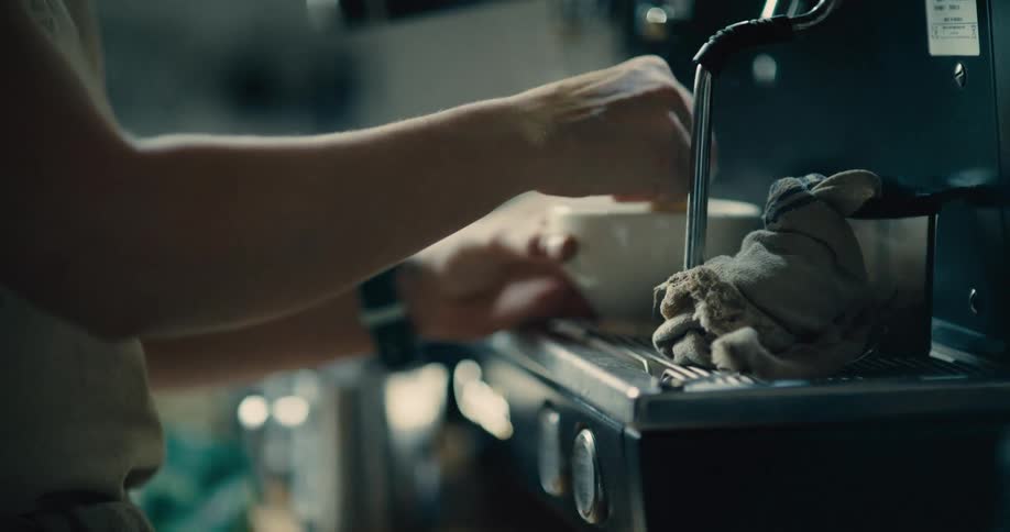 Person steaming a beverage with a coffee machine