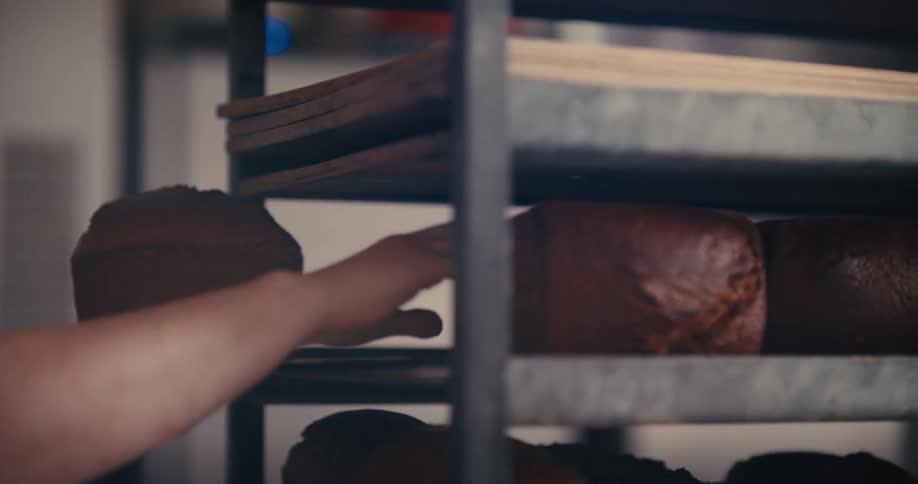 A baker loads loafs of bread onto a shelf