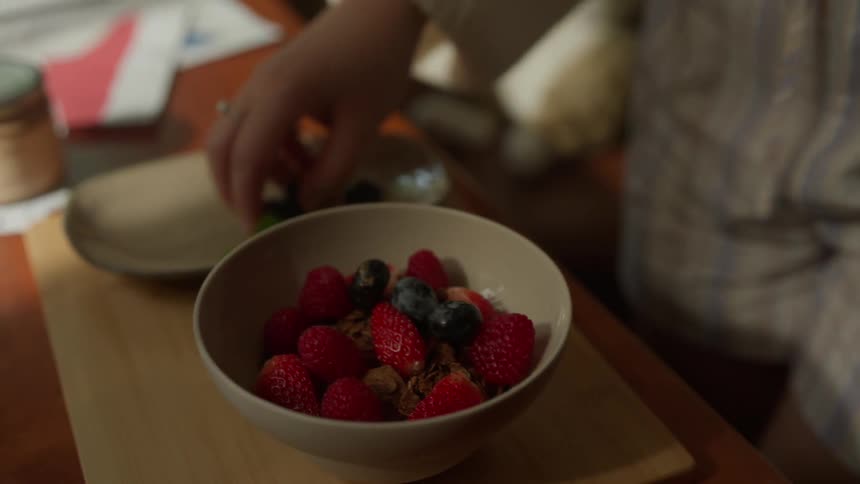 The woman puts fruit on her cereal