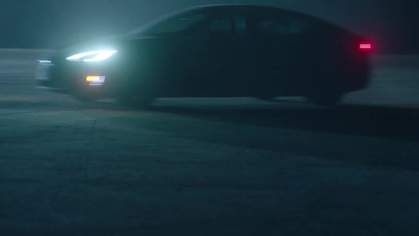 A car drives at night with its headlights on