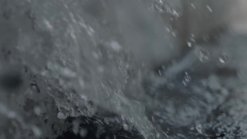 Stream of water hitting against a rocky wall outdoors
