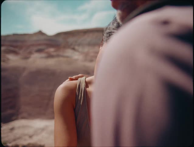 The man is hugging a woman by the mountains