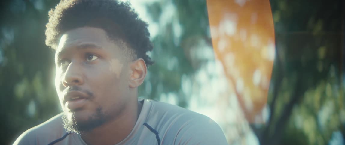 A focused young athlete catches his breath outdoors backlit by intense sunlight