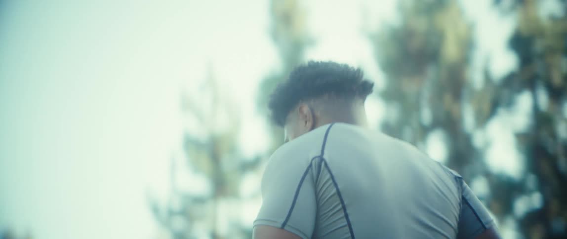 An athlete intensely runs then immediately stops to catch his breath in the bright sunlight