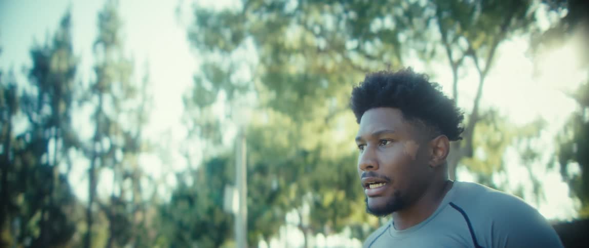 Young black man running in place on a field then stopping with an exhausted but determined face expression outdoors during day time