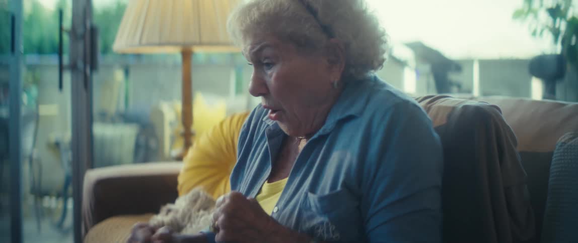 Elderly woman sitting in her living room cheers while watching a sports event