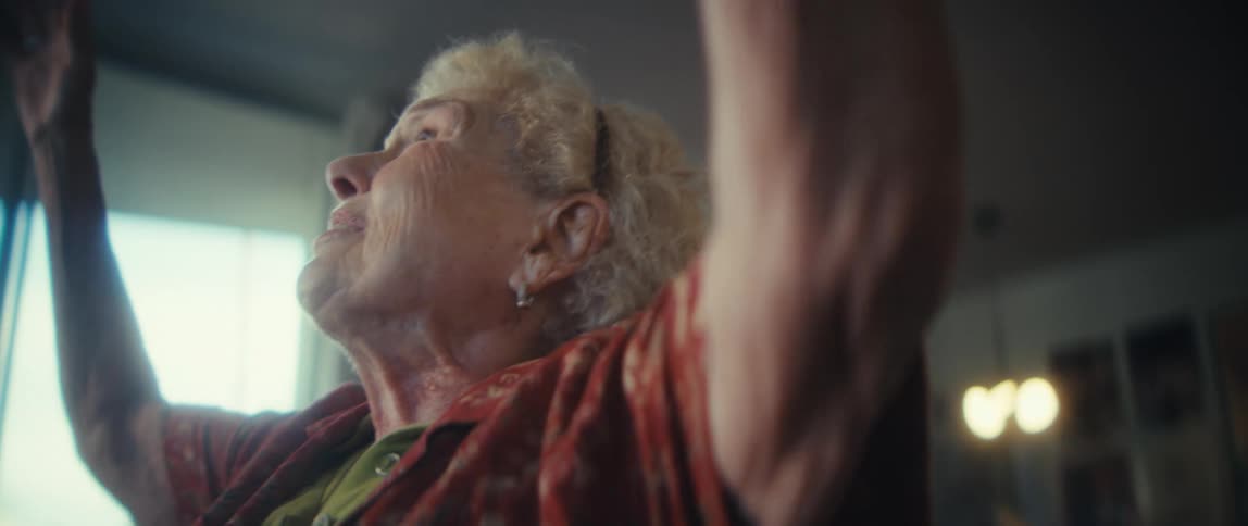With a look of pure joy an elderly woman sings passionately and raises her arms in celebration