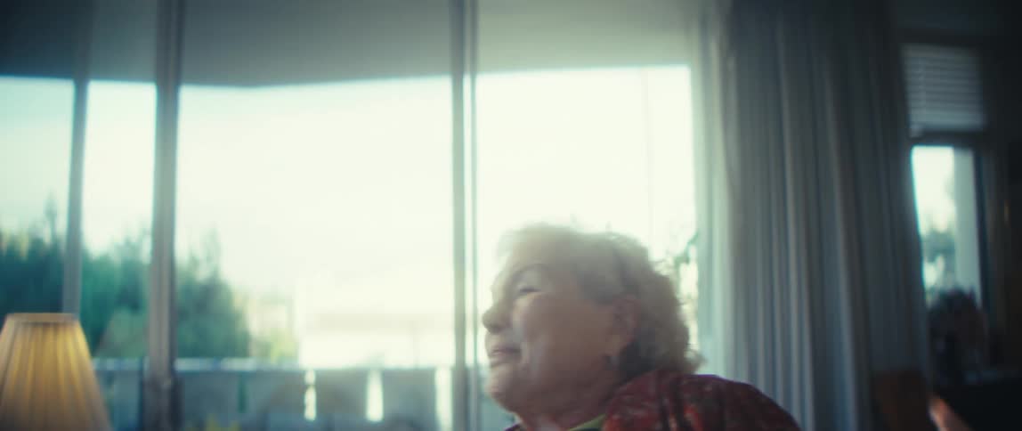 A joyful elderly woman sings dances and smiles in her sunlit living room