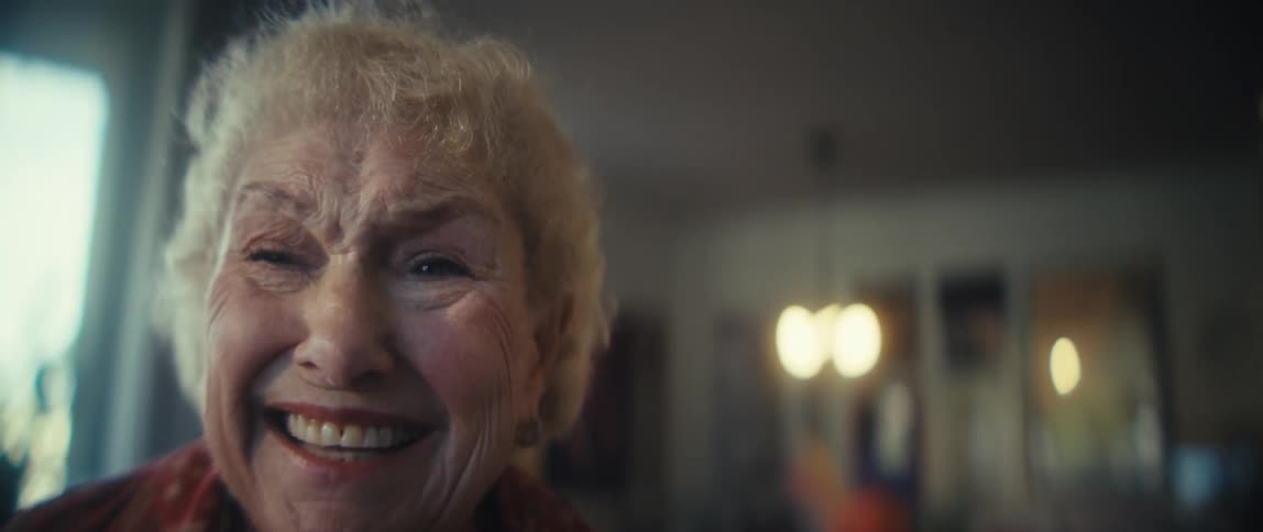 Elderly woman smiles and sways in place while singing alone at home