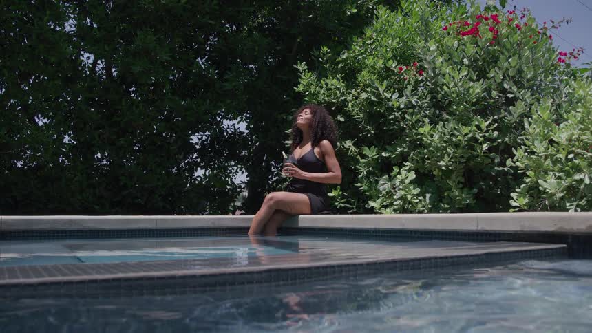 The woman is having a drink poolside