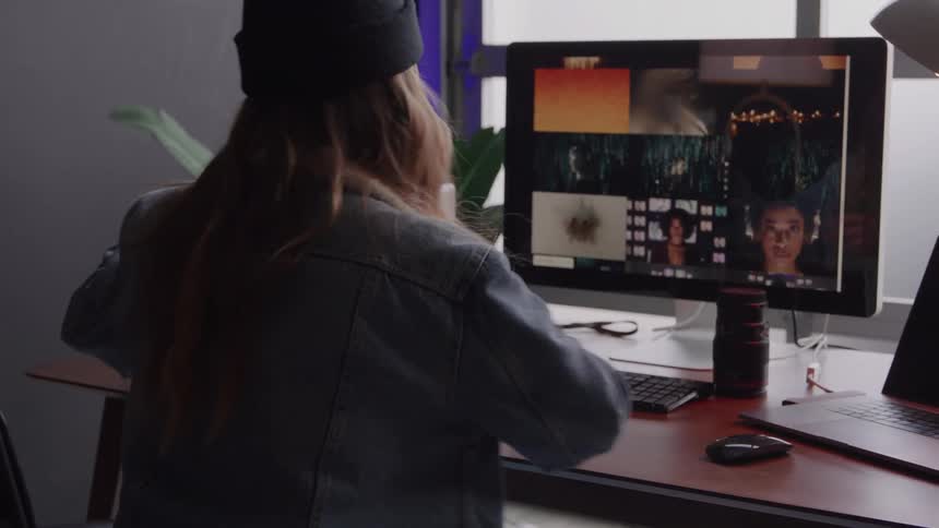 Person adjusting headphones while working on video editing at the computer