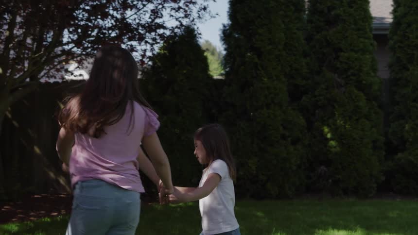 Siblings hold hands while playing outside in their backyard