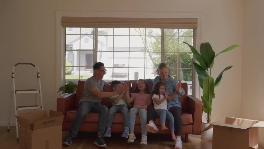 Family sitting on the couch celebrating with a highfive after moving in