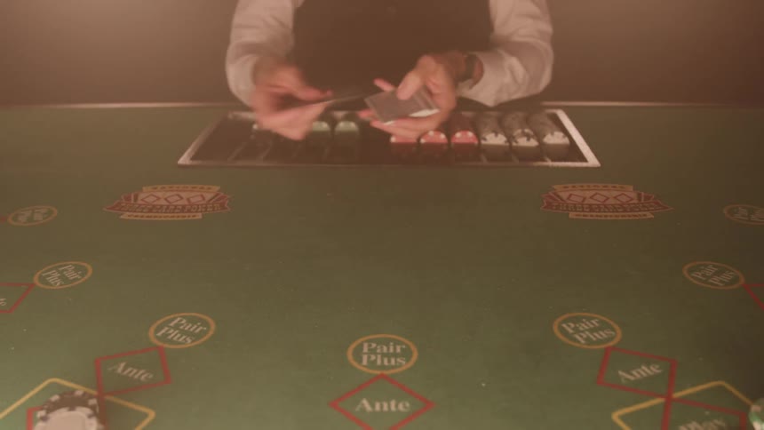 A dealer dealing several cards on a table with some writing and chips in front of him