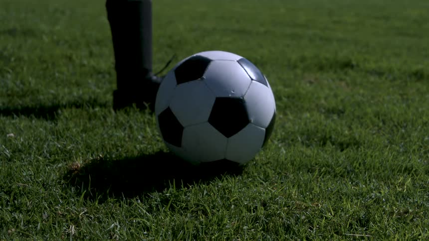 Soccer play runs forward and kicks a soccer ball on a summer day