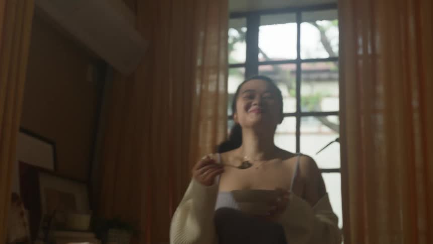 Woman smiles while eating and dancing in her apartment