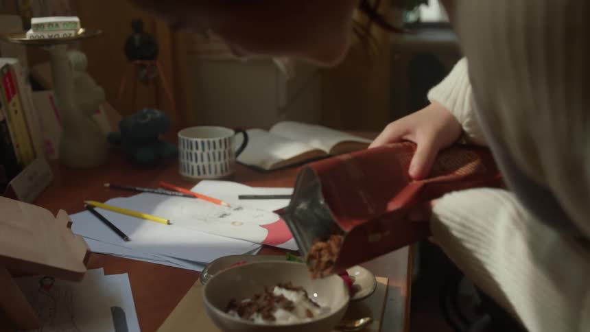 Woman walks into her bedroom and pours food into a bowl before eating