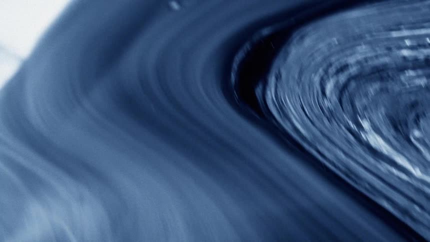 Blue ink in motion forming swirls and fluid curves