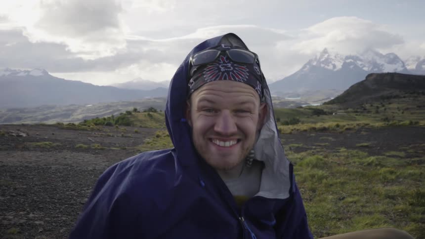 A hiker smiles in the mountains on a windy day