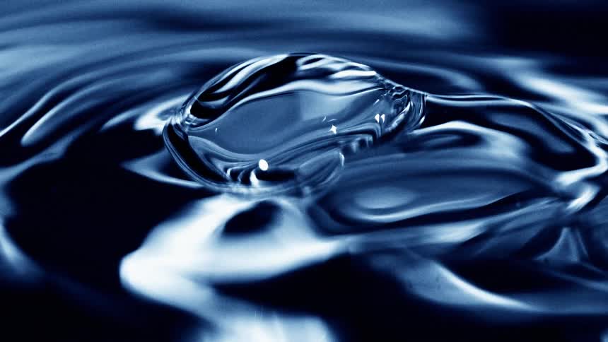 Bubble forms on the surface of a blue liquid under soft lighting
