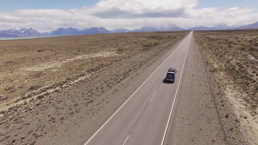 Van drives down a road in the middle of a desert