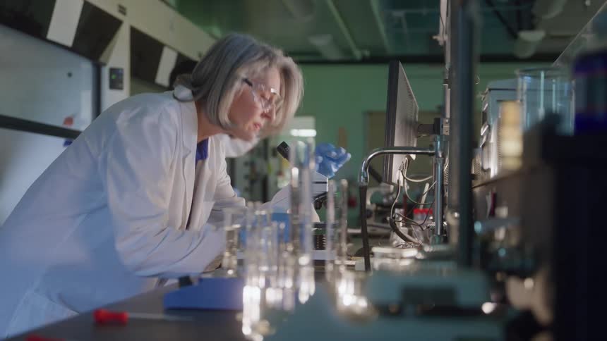 Scientist analyzing samples through a microscope inside a laboratory