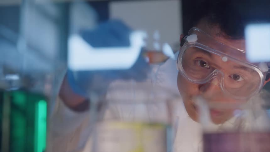 Scientist carefully observing experiments with colored liquids in a laboratory