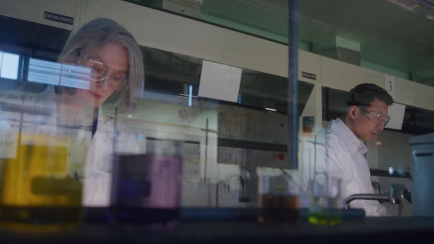 The scientists move beakers around while working in the lab