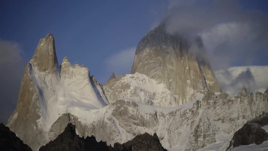 Clouds floating over tops of snowy mountains