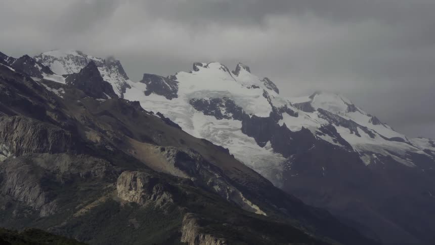Clouds float over a snowy mountain peak