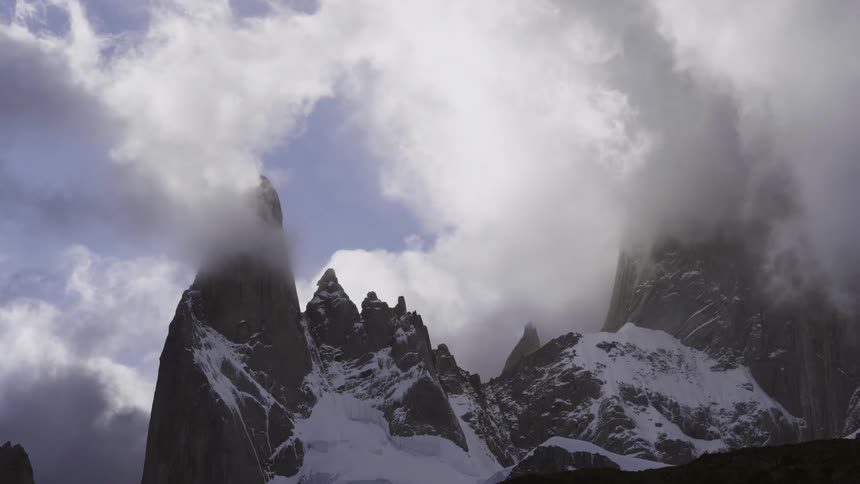 Clouds float over a snowy mountain peak