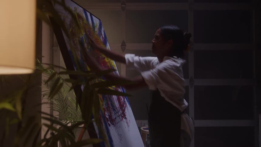 The woman uses her hands to paint the canvas instead of a brush