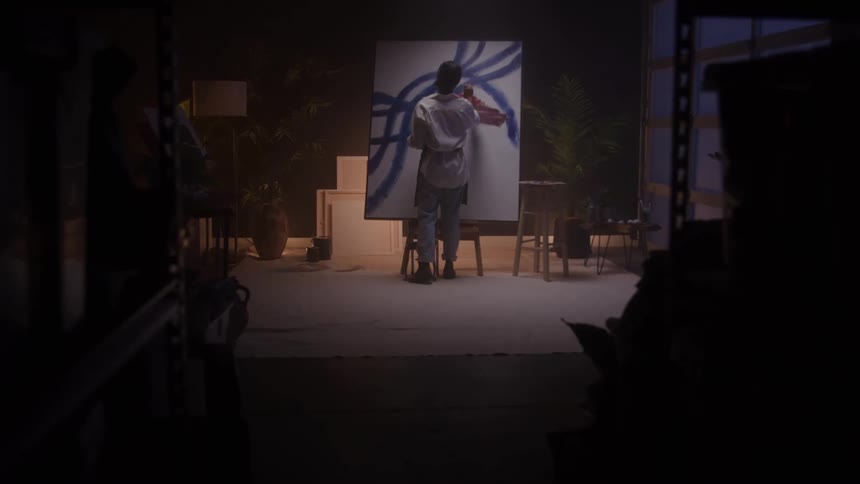 The woman paints on a large canvas in the studio
