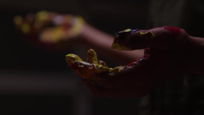 Close up of a black female artists palms and fingers covered with multicoloured paints