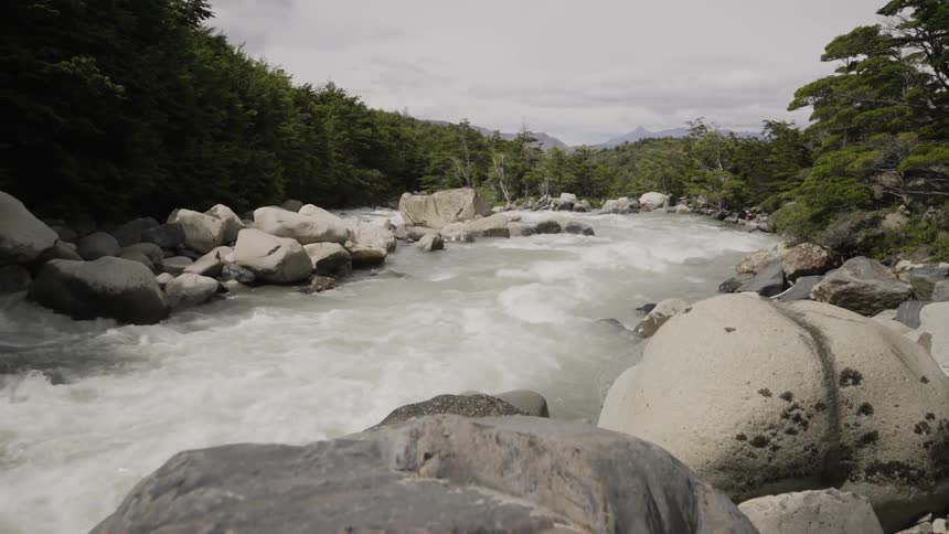 A river flows by large boulders in the woods