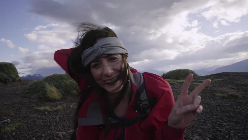 Woman smiling in mountain wilderness on cloudy and windy day