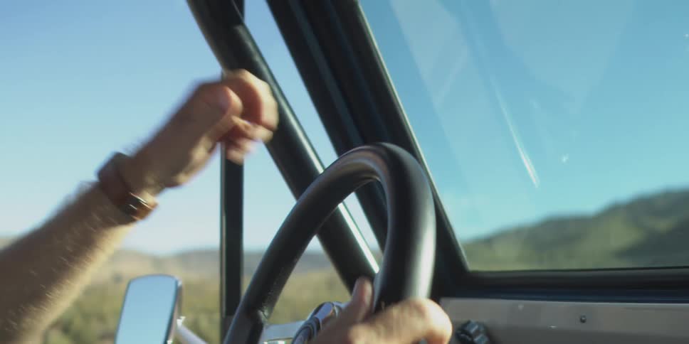 The man points out the window while driving
