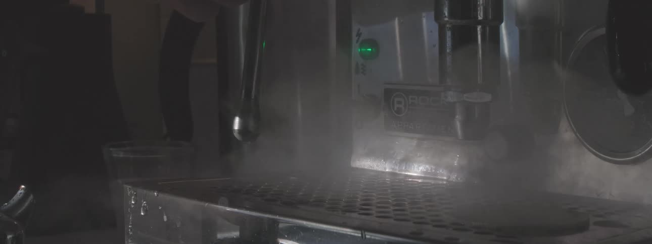 Coffee machine releasing steam while brewing a drink