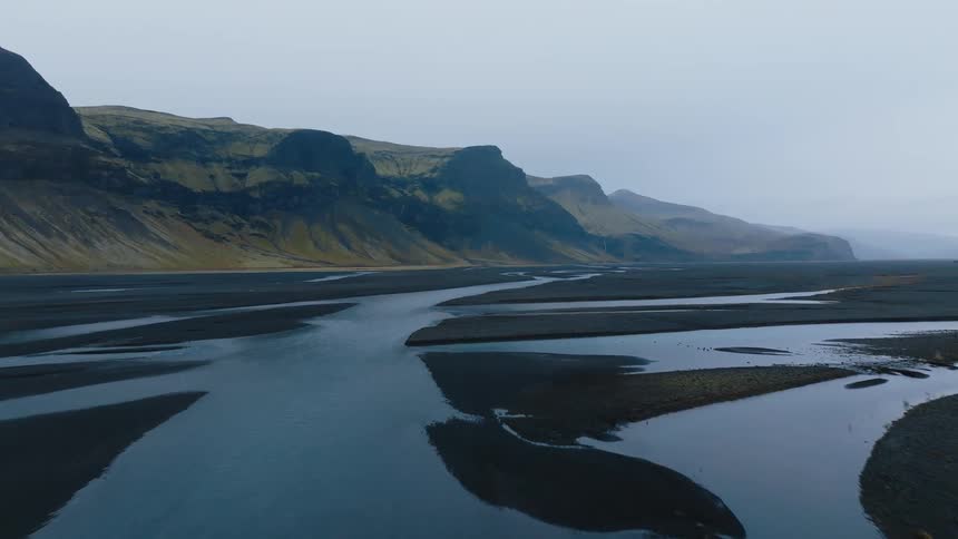 Winding streams flow across a dark plain surrounded by mountains