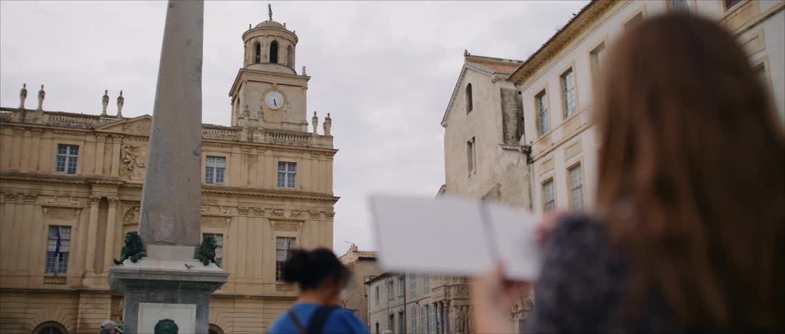 Woman observing a historic building and sketching in a notebook in front of an obelisk