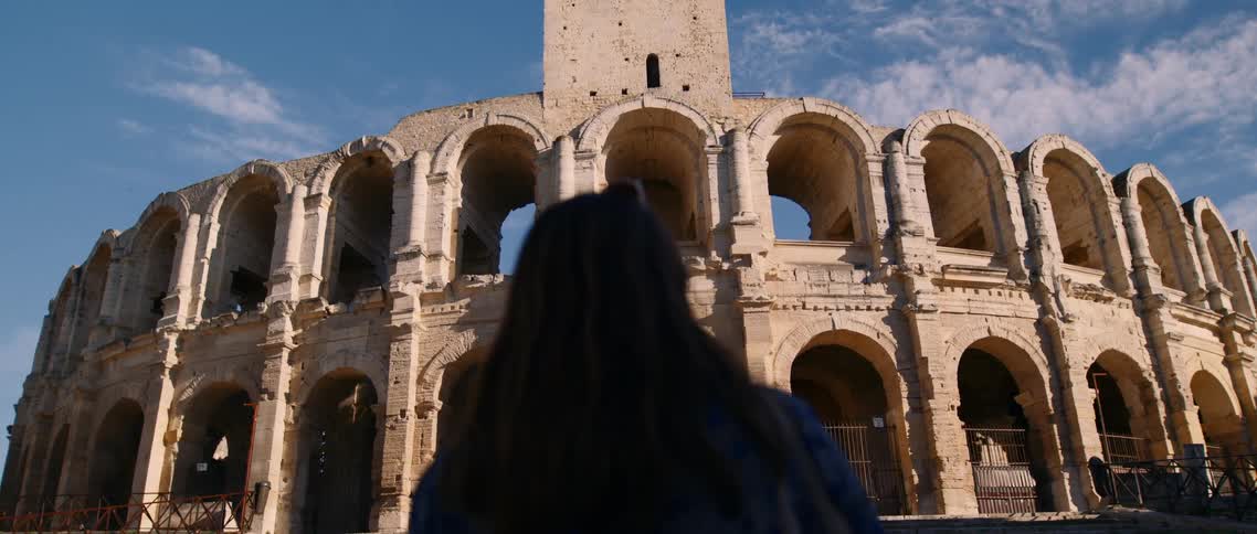A woman stands before a large structure