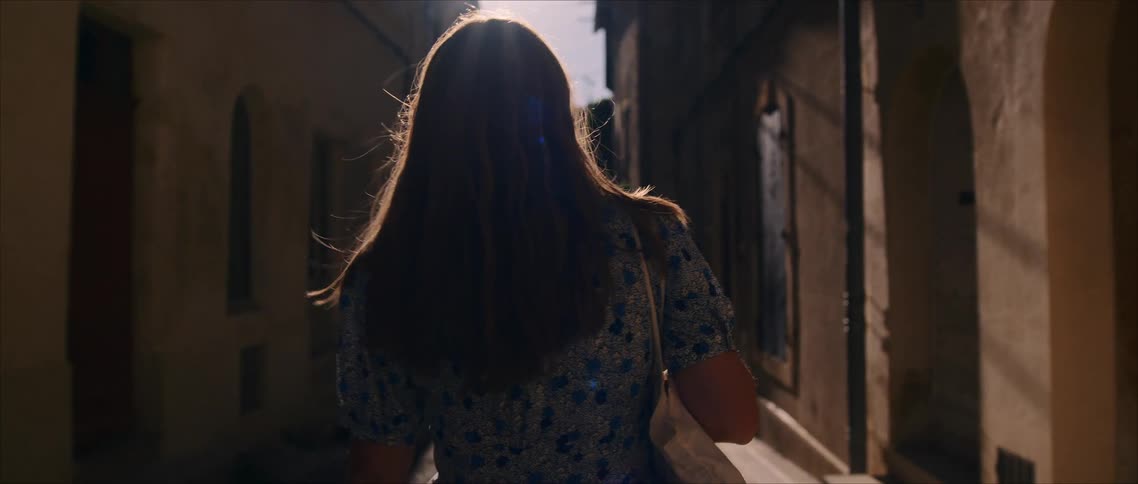 The woman walks through the alley on a sunny day