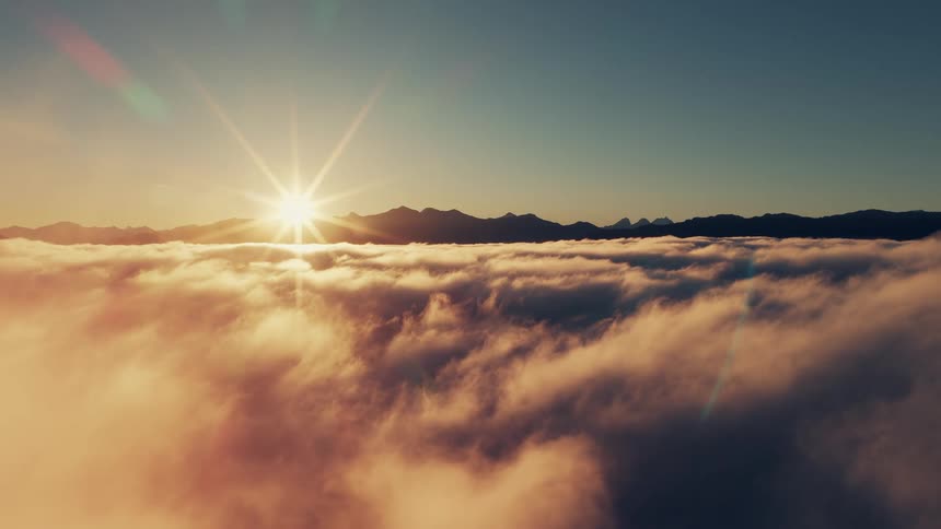 Sun rising over a sea of clouds in front of the mountains