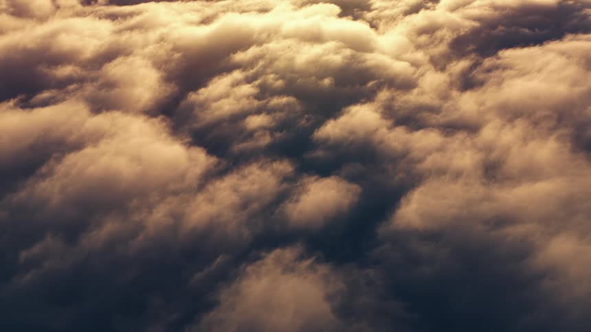 Drone flies through clouds revealing the morning sun illuminating the mist
