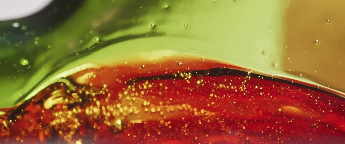 Fizzing red beverage fills a green bottle