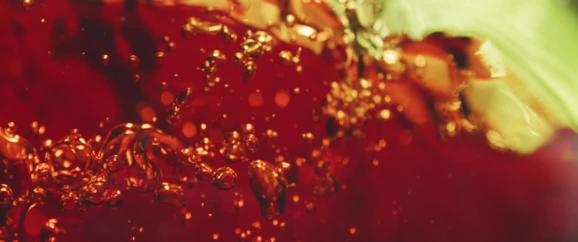 Close up of a red drink pouring into a green glass cup