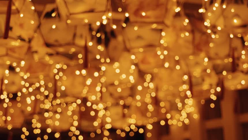 A ceiling filled with hexagonal paper lanterns glows warm orange as delicate string lights dangle with tassels