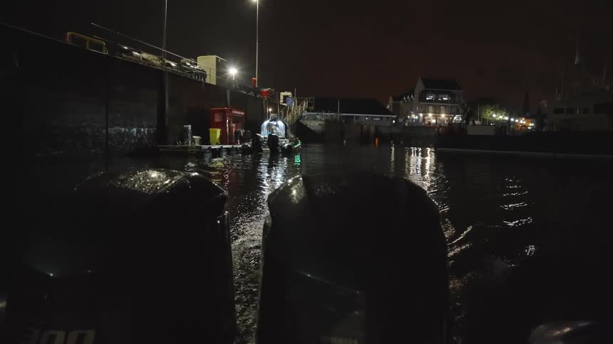 Men working on a docked boat at night in a lit area