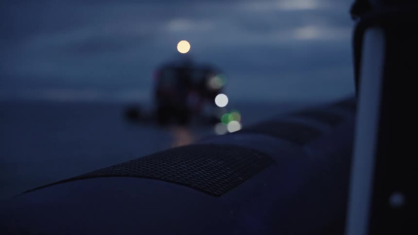 Boat on the sea at dusk with blurred lights in the background