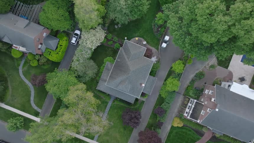 Aerial view of houses with yards and trees in a suburban neighborhood